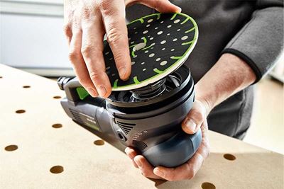 Festool 샌더에 샌딩 패드를 부착하는 작업자의 모습